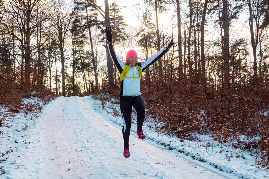 Vinterlöpning i skogen på snöig skogsväg.